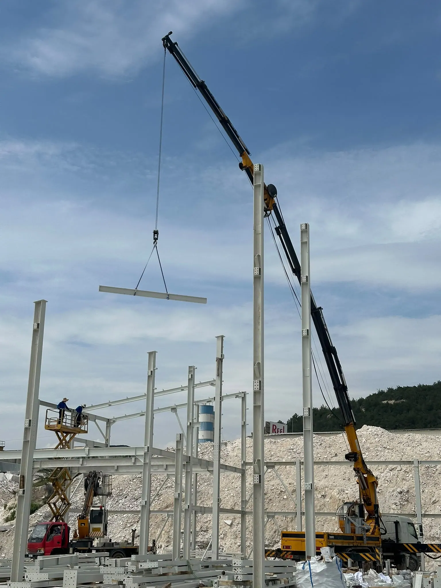 Kamyon üstü vinçle kaldırılan çelik kiriş, makaslı platformda montaj ekibi
